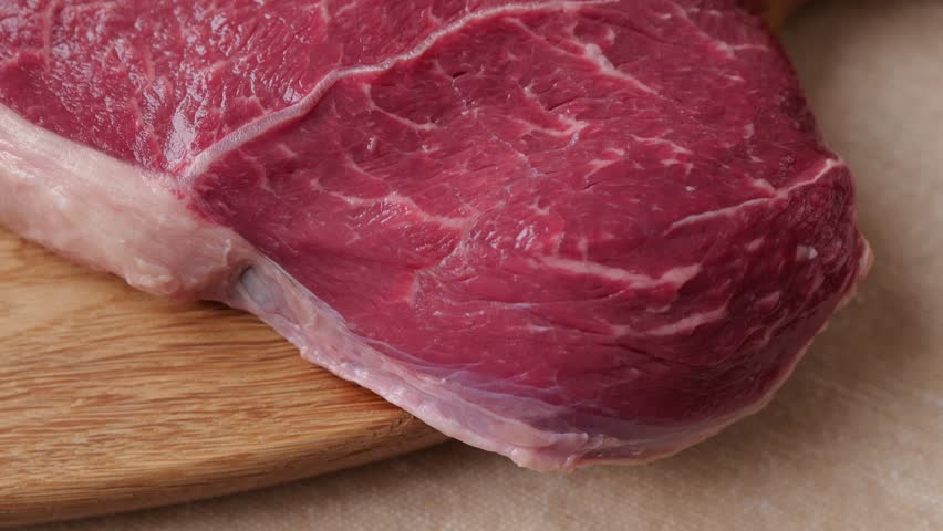 Raw beef steak placed on a wooden cutting board