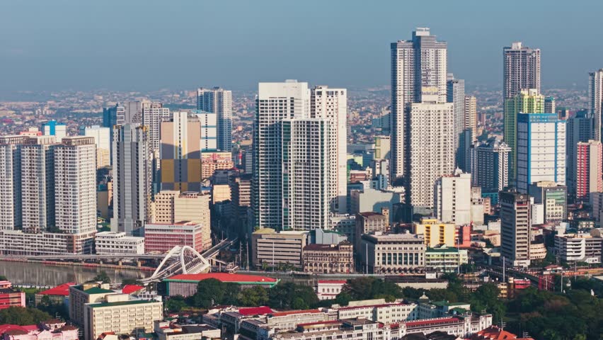 Lowering altitude from Intramuros revealing bright tropical Manila skyscrapers