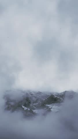 Snowy Mountain Peaks Emerging from Clouds.

Snow-covered mountain peaks appearing through low-moving clouds in the Alps.