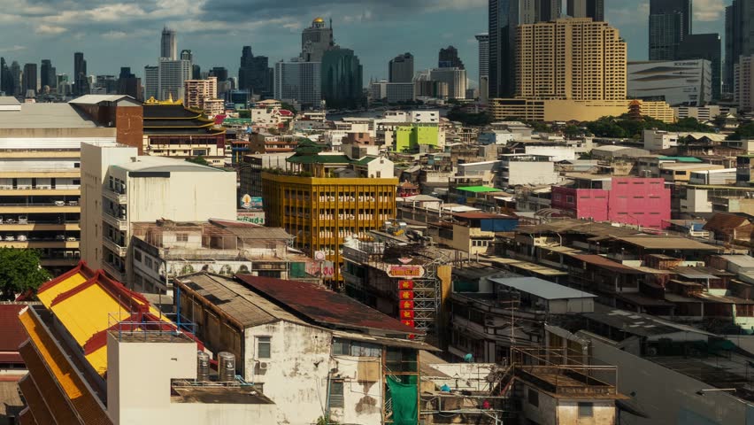Bangkok, Thailand. Aerial view of a cityscape with a mix of modern skyscrapers and older buildings, including a prominent yellow tower with a golden emblem.