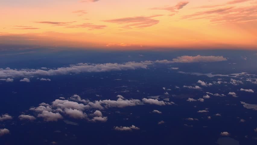 Aerial view of a sunset over a landscape with clouds and a body of water.
