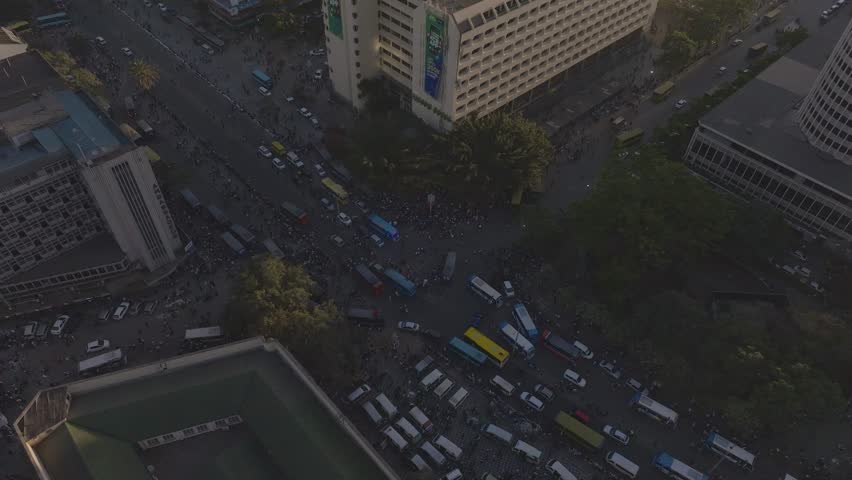 Aerial drone shot of busy commercial street in Nairobi city, with Matatu, buses, and people congested on the streets.