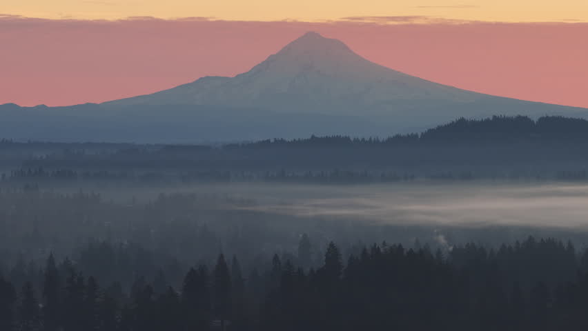 At dawn, the scenic Mount Hood rises from the forested landscape of northern Oregon. This iconic Pacific Northwest mountain is part of the Cascade Mountain Range.