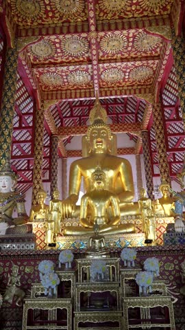 Interior of the grand prayer hall at Wat Suan Dok featuring a large golden bronze Buddha statue in the Bhumisparsha Mudra position with ornate Lanna architecture, Chiang Mai, Thailand