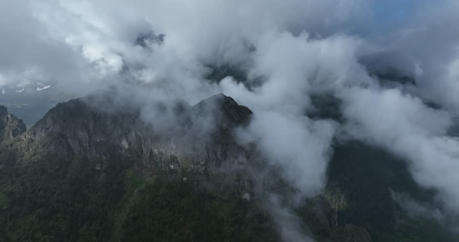 Aerial footage of beautiful high altitude snowcapped mountains and forest landscape