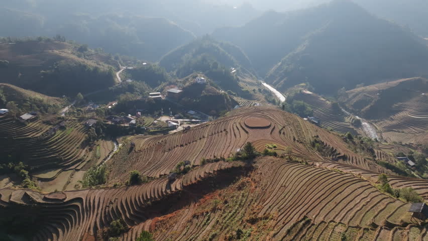 Gliding aerial footage presents a wide scenic ridge of rice terraces with layered mountains beyond at sunrise in Mui Giay, Mu Cang Chai district, Yen Bai province, Vietnam.
