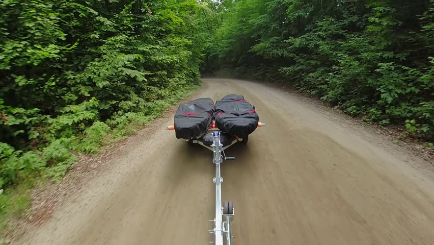 Kayaks on boat trailer with kayaks covered with waterproof dustproof UV protection fabric, transported by truck or car. Water sport fishing. Going to boat launch at lake. Boat trailer fishing kayaks.