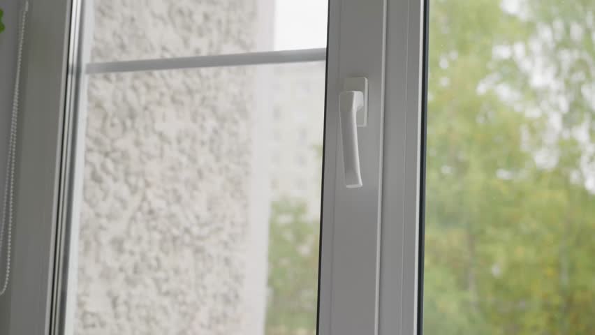 Close-up shot of a human hand opening a window by turning the handle. Fresh air concept, ventilation process and everyday home routine inside an apartment. High quality 4k footage