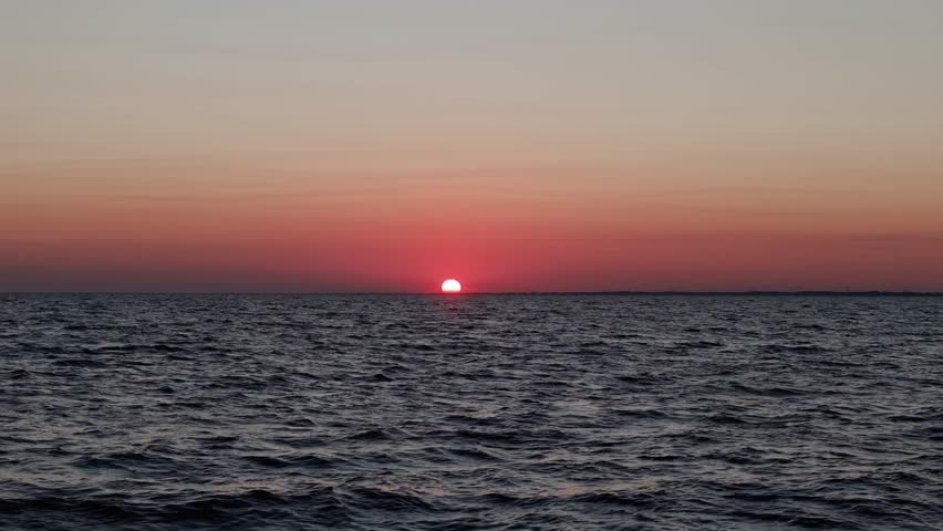 Cinematic dolly-forward footage of a peaceful sunset over Lake Pontchartrain in Louisiana, featuring calm water and warm evening sky.