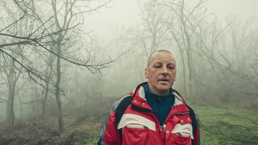 Introspective winter stroll of senior man in foggy woodland