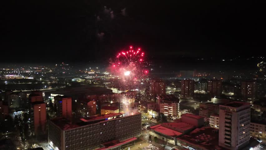 Colorful fireworks exploding over city skyline at night during a festive celebration. Bright lights illuminating the urban landscape.