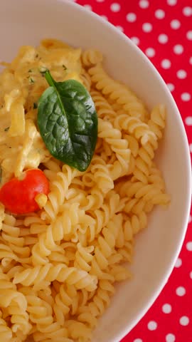 Pasta with creamy sauce and cherry tomatoes served in a bowl on a table