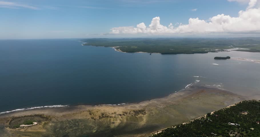 Tropical wide bay with a long shoreline and green hills stretching inland. Siargao, Philippines.