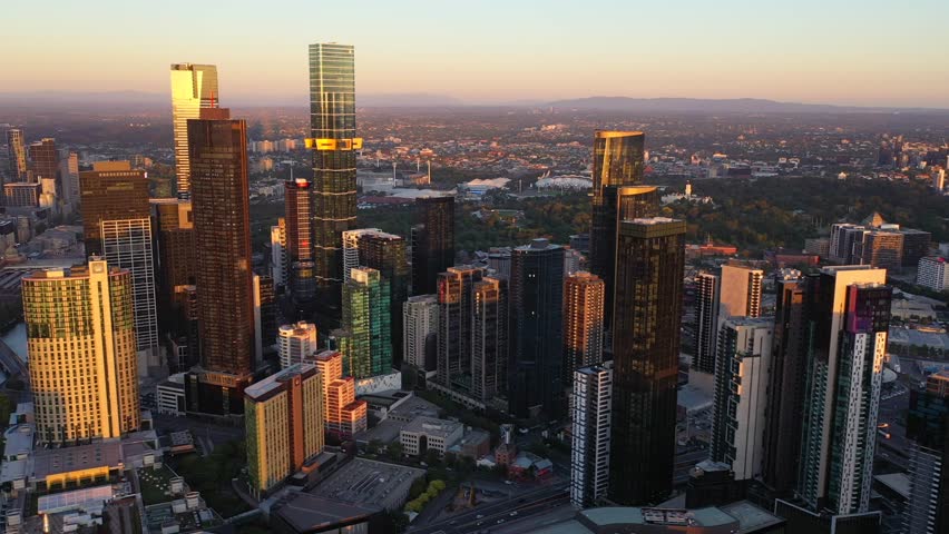 Low altitude drone video of Melbourne CBD skyline at sunset with modern skyscrapers, high rise towers and urban cityscape in Australia