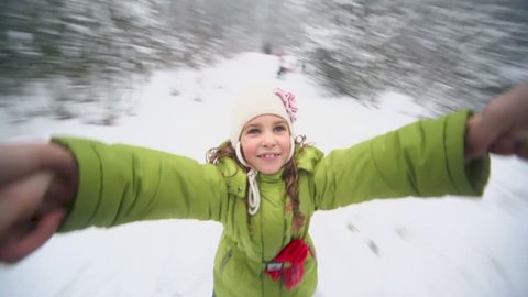 Hand holds little girl which flies above snow at background of winter forest