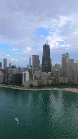 Vertical aerial view of Chicago skyline over Lake Michigan with downtown skyscrapers and calm water surface, iconic city architecture, summer atmosphere, scenic travel cityscape