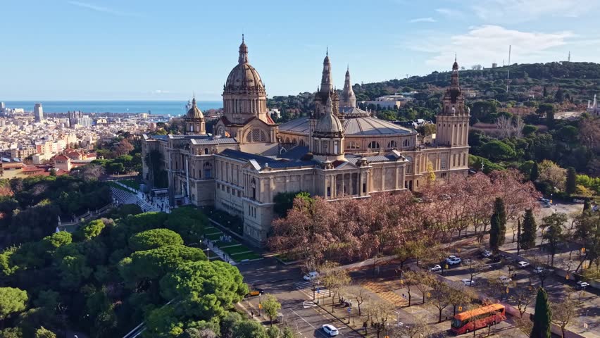 Drone establishing shot of the Museu Nacional d’Art de Catalunya housed in the Palau Nacional on Montjuïc, Barcelona, revealing its monumental domes and panoramic setting above the city.