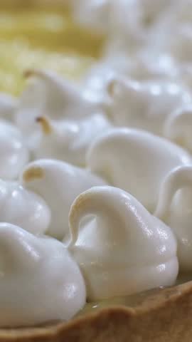 Macro shot of white meringue peaks on a lemon tart being toasted to a golden brown color with heat.