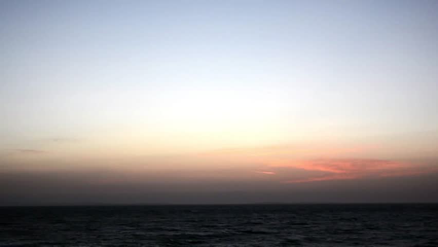 Hyperlapse view of the sun setting over the sea in Tangier, Morocco, showing fading daylight, soft horizon glow, calm water, and peaceful evening atmosphere