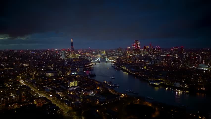 Establishing night view of the illuminated cityscape of London, UK, with river Thames, Tower Bridge and City skyscrapers