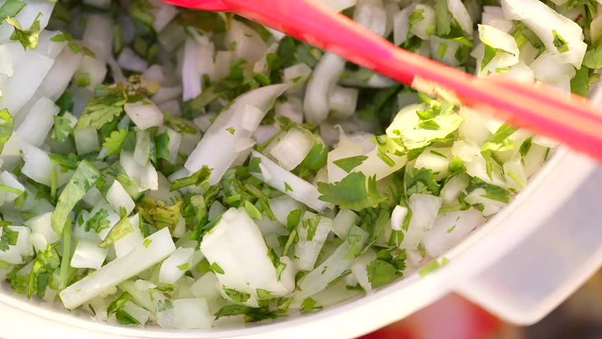 Close-up view of fresh chopped cilantro and onion, highlighting vibrant green and white colors, texture, and freshness for Mexican cuisine, garnishes, and street food preparation.