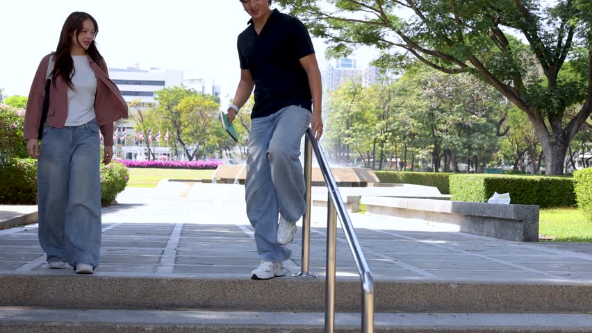 A smiling young man slides down a metal handrail while his friend watches outdoors