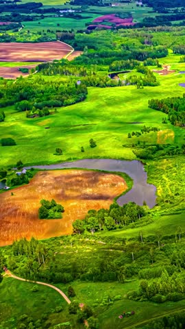 Shadows of clouds project onto a green landscape, seen from above. Vertical shot.