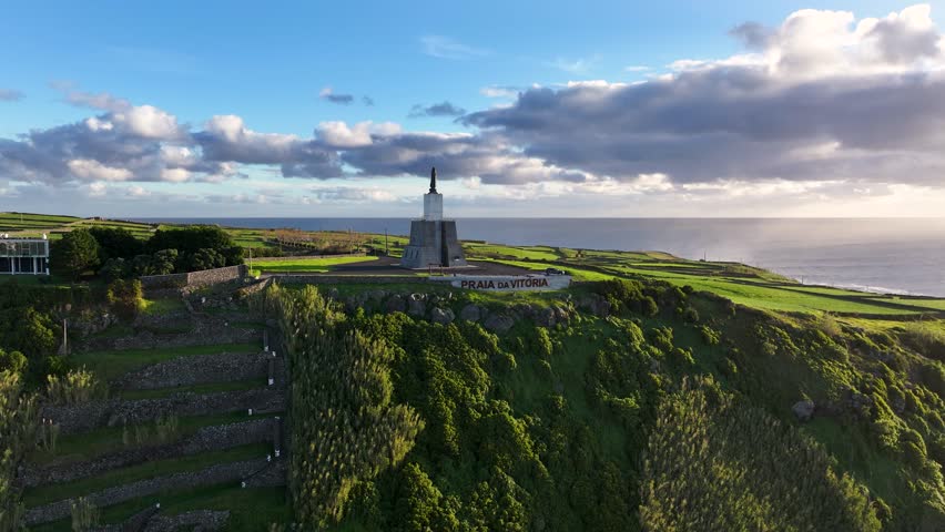 Sunrise aerial toward Serra do Facho viewpoint with statue in Praia da Vitória