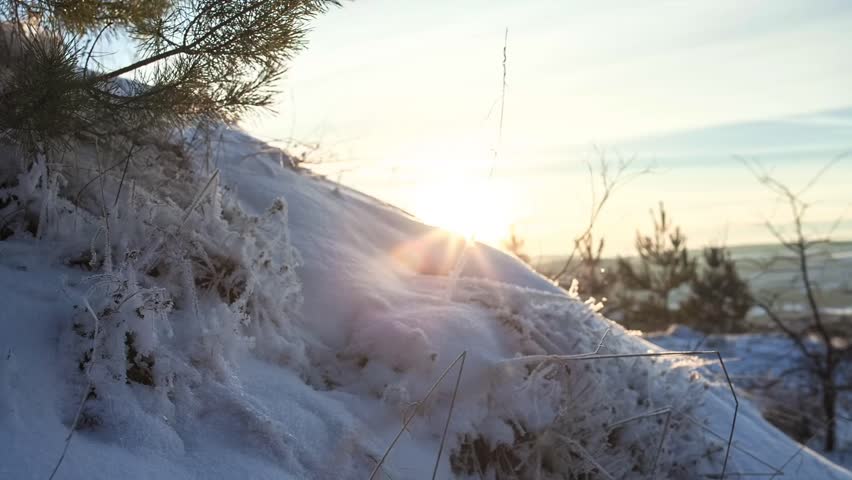 Beautiful sunrise over a pristine snowy landscape. Warm golden sunlight hitting the white snow dunes, creating long shadows and a peaceful winter atmosphere.