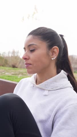 Young athletic woman in sportswear sitting on a bench eating a chocolate bar after a workout