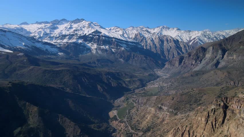 Aerial view of snow capped mountain range above deep valley with ridges
