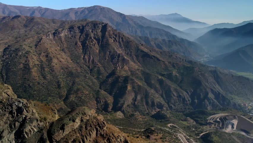 Tilting down reveal of winding mountain road through rocky ridges and valleys
