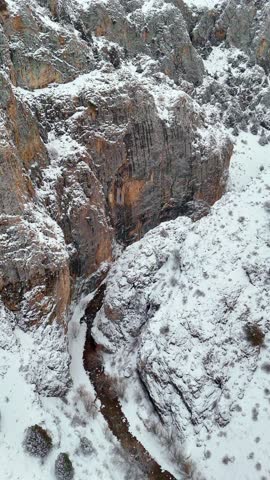 Majestic winter canyon with frozen river and snowy rocks, aerial view.