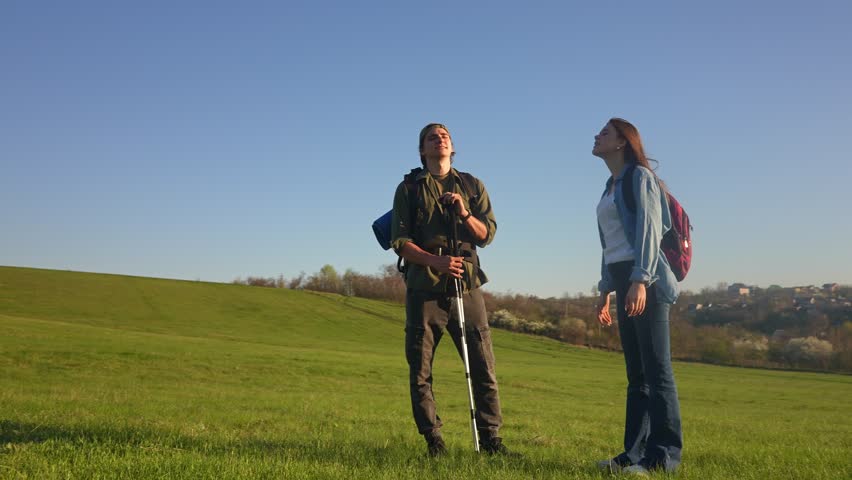 A joyful couple embraces nature while hiking on a sunny day in the countryside, celebrating freedom. Slow motion