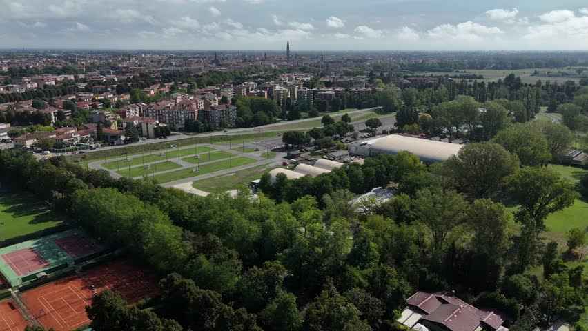 Aerial view of Cremona cityscape meeting countryside in Lombardy, northern Italy with Torrazzo bell tower in the background and sport facilities in the foreground