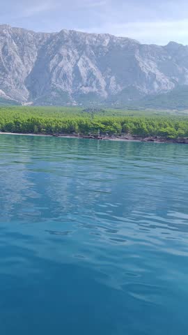 View of the Croatian coastline with high cliffs and green forests from the sea. Concept of marine tourism, scenic nature exploration, and peaceful summer holiday in the Mediterranean