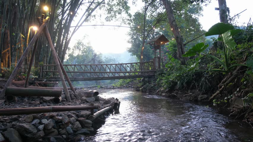 A small canal flowing down under wooden bridge in the forest