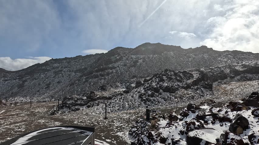Snow falling over the volcanic landscape of Tongariro National Park, New Zealand, during the winter season