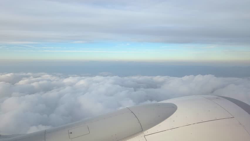 Airplane Wing Over Cloudscape: Tranquil Flight Above Fluffy Clouds at Dawn