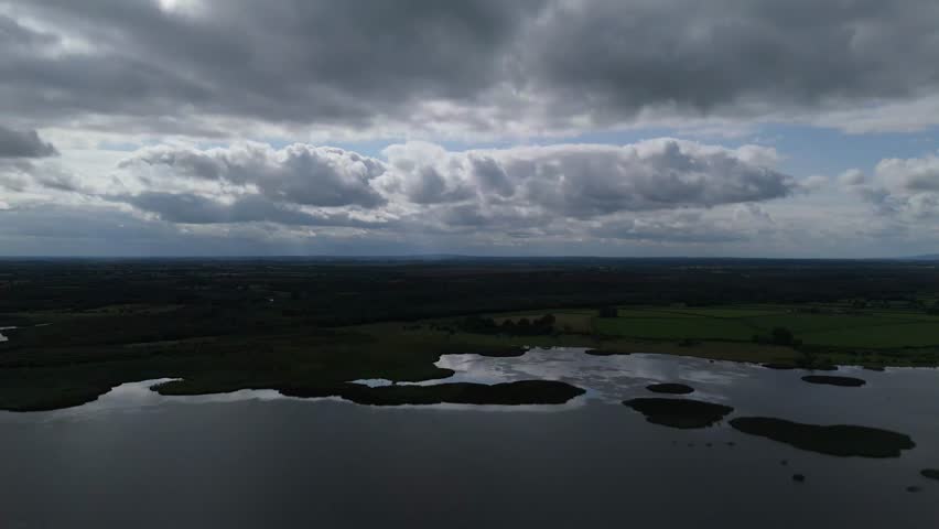 A cloudy sky with a lake and a field.