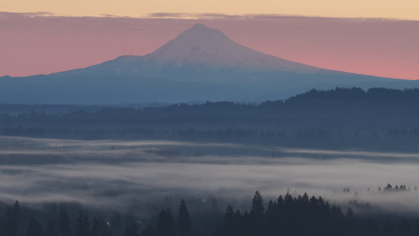 At dawn, the scenic Mount Hood rises from the forested landscape of northern Oregon. This iconic Pacific Northwest mountain is part of the Cascade Mountain Range.