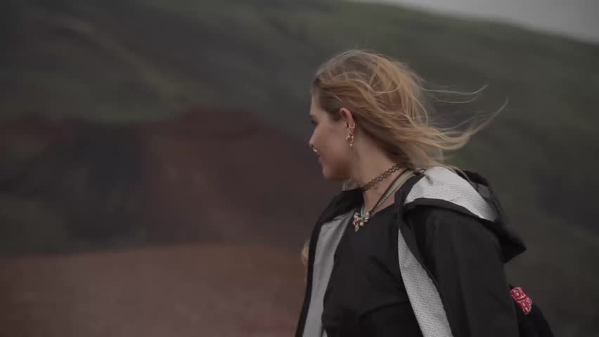 Young female traveler looking at the mount etna landscape with her hair blowing in the wind