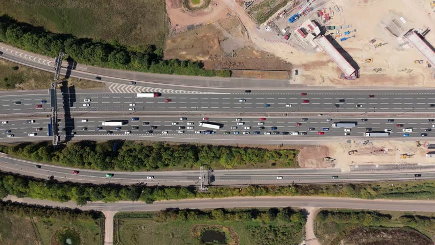 Top down aerial view of M1 motorway traffic flowing past HS2 high speed rail construction site and civil engineering works in Birmingham England UK