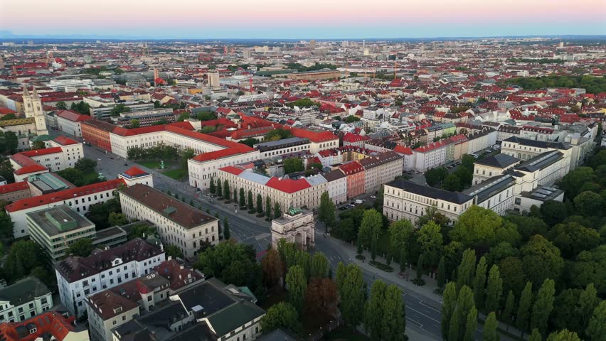 Aerial summer view of Munich at sunrise, featuring the iconic Siegestor triumphal arch, Bavaria statue with lions, Ludwigstrasse, and Leopoldstrasse, perfect for travel and architectural video content