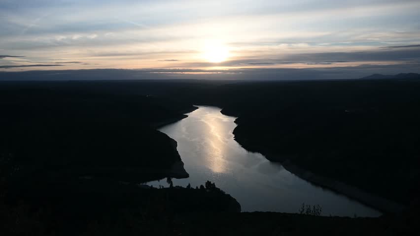Fixed view of sunset over river valley in Monfrague Spain with golden reflection on water and layered hills peaceful travel nature background