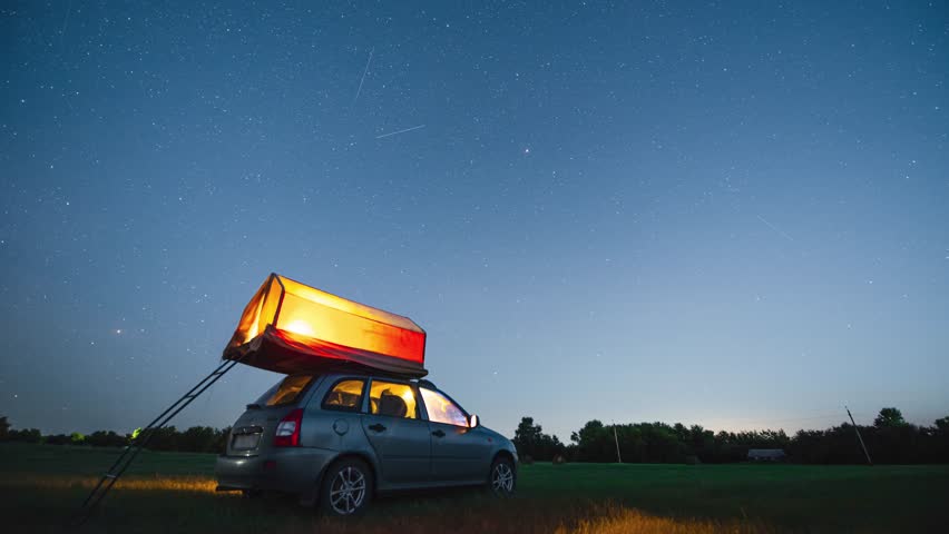 Timelapse, starry sky and Milky Way above a car and a tourist tent