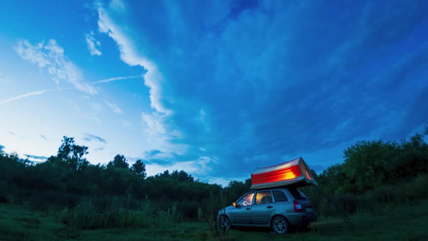 Timelapse, starry sky and Milky Way above a car and a tourist tent