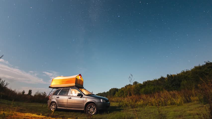 Timelapse, starry sky and Milky Way above a car and a tourist tent
