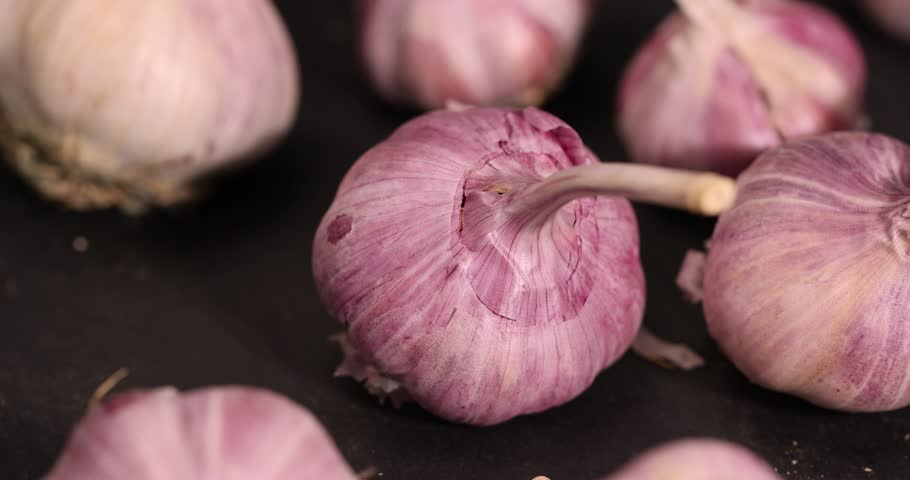 ripe garlic is  on a black table in the kitchen, garlic spices are on a black slate board in the kitchen over cooking