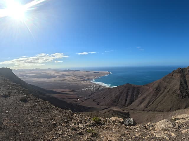 beautiful panoramic view from a mountain top overlooking the volcanic coastline of Lanzarote Canary Island, showing Atlantic Ocean, rugged terrain, and dramatic island landscape